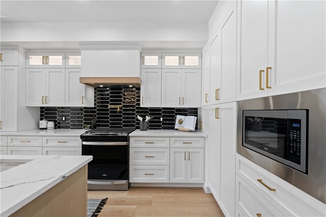 kitchen with backsplash, white cabinetry, appliances with stainless steel finishes, and light wood-type flooring