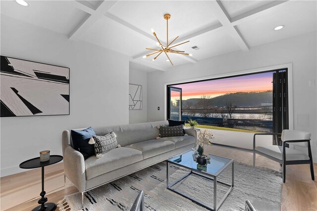 living room featuring beam ceiling, light wood-type flooring, coffered ceiling, and a chandelier