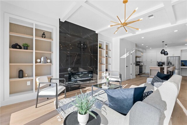 living room featuring an inviting chandelier, coffered ceiling, built in shelves, and light wood-type flooring