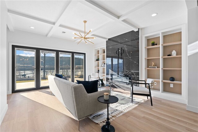 living room featuring coffered ceiling, beamed ceiling, a notable chandelier, a mountain view, and light hardwood / wood-style flooring