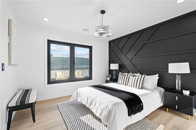 bedroom featuring an inviting chandelier and light hardwood / wood-style floors