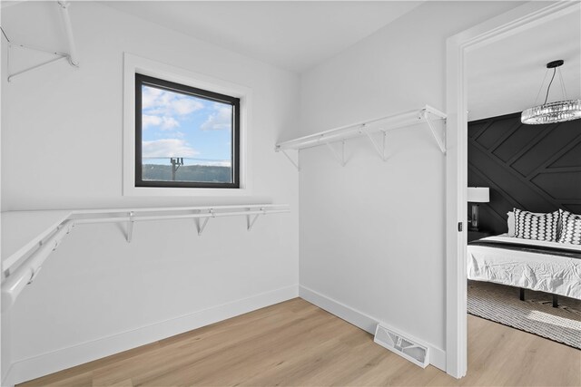 walk in closet featuring a notable chandelier and light hardwood / wood-style floors