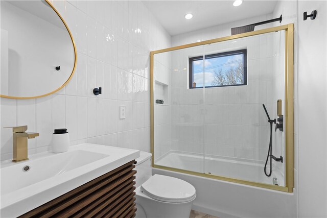 full bathroom featuring tile walls, combined bath / shower with glass door, toilet, and vanity