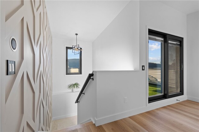 staircase featuring an inviting chandelier and light hardwood / wood-style flooring