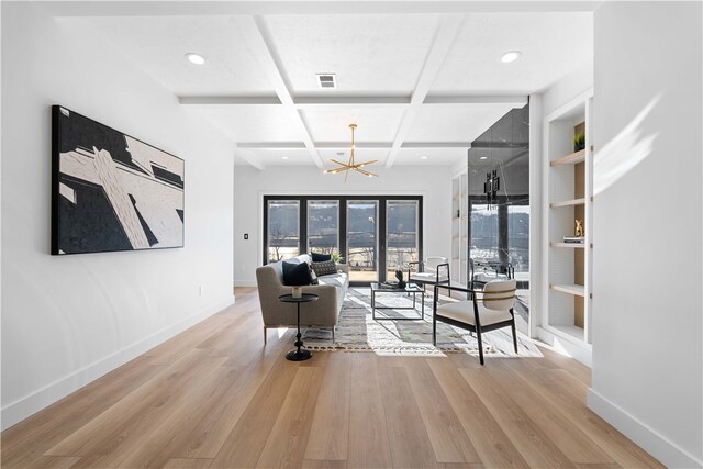 living room featuring coffered ceiling, a notable chandelier, beamed ceiling, and light hardwood / wood-style floors