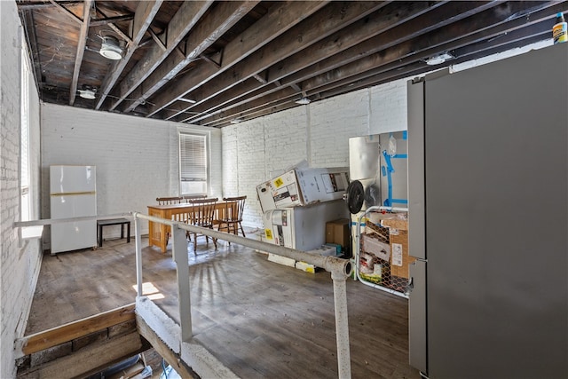 basement featuring white fridge and brick wall