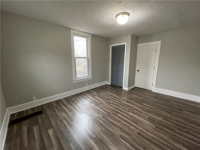 unfurnished bedroom featuring a closet, dark hardwood / wood-style floors, and a textured ceiling