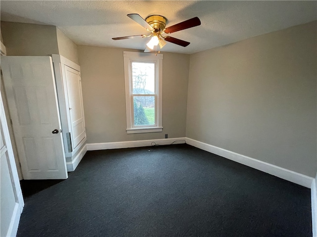 unfurnished bedroom featuring ceiling fan, a textured ceiling, and dark carpet