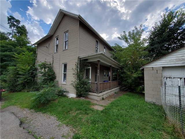 view of side of property with covered porch and a yard