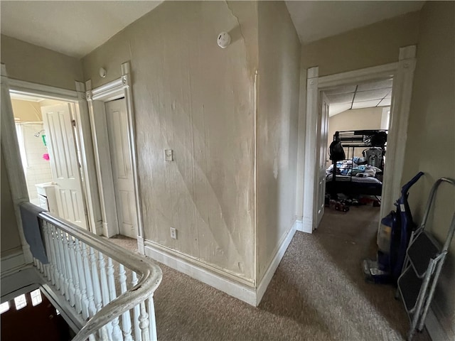 hall with lofted ceiling and dark carpet