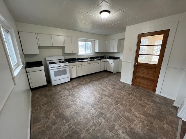 kitchen with white cabinetry, white gas stove, and sink