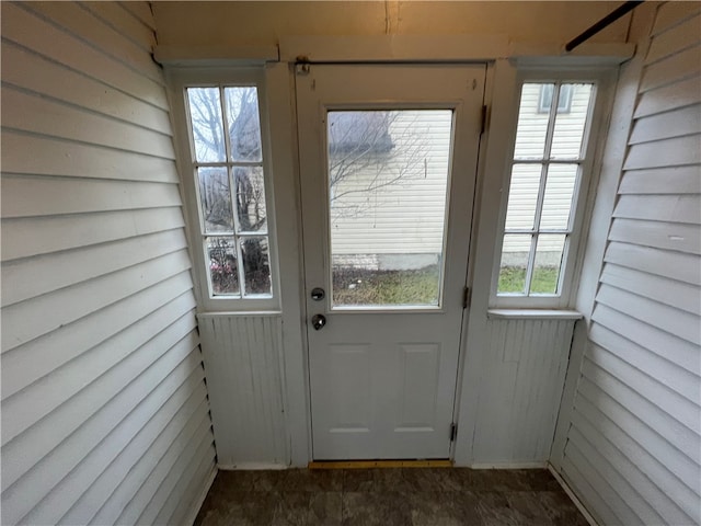 doorway featuring wooden walls and a wealth of natural light