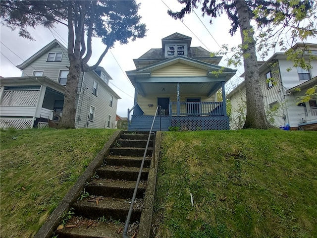 bungalow-style house featuring covered porch and a front yard