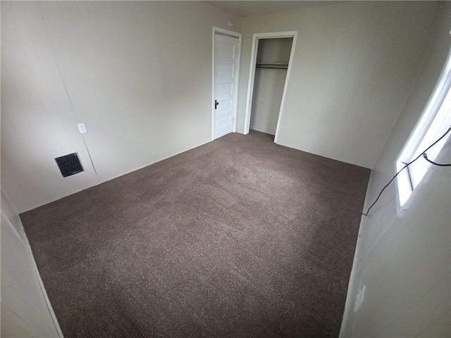 unfurnished bedroom with a closet and dark colored carpet