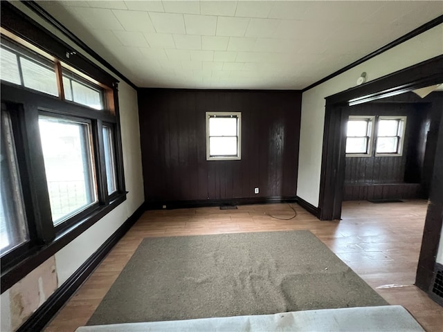 unfurnished room featuring light hardwood / wood-style flooring, wooden walls, and plenty of natural light