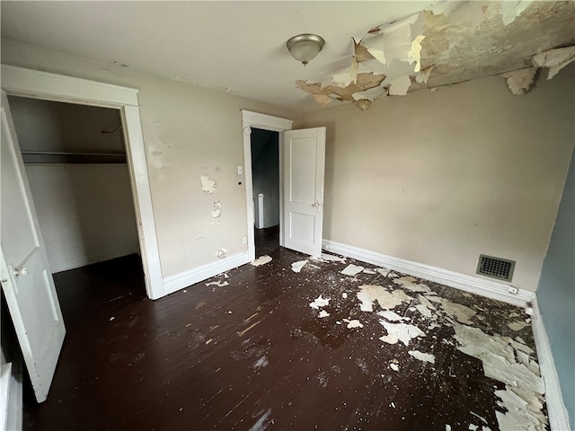 unfurnished bedroom featuring dark hardwood / wood-style floors and a closet