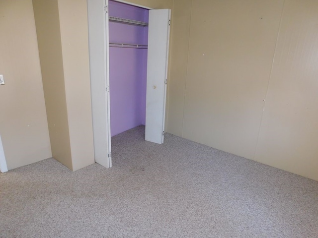 unfurnished bedroom with a closet and light colored carpet