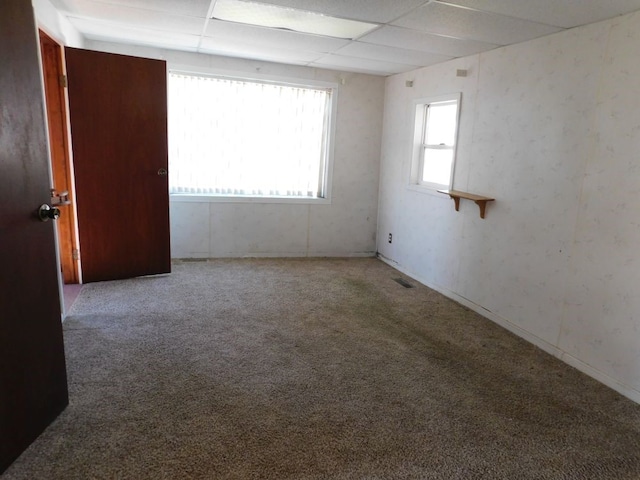 empty room featuring a paneled ceiling and carpet floors