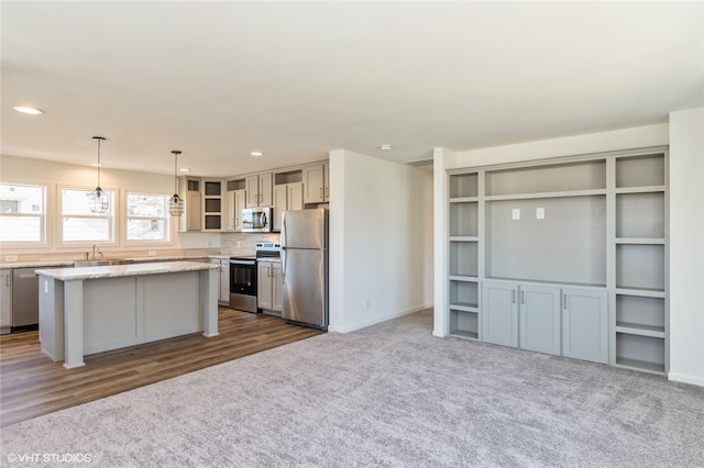 kitchen featuring a kitchen island, stainless steel appliances, sink, pendant lighting, and dark hardwood / wood-style flooring