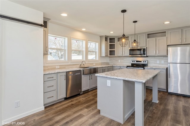 kitchen featuring a center island, appliances with stainless steel finishes, decorative light fixtures, and dark hardwood / wood-style flooring