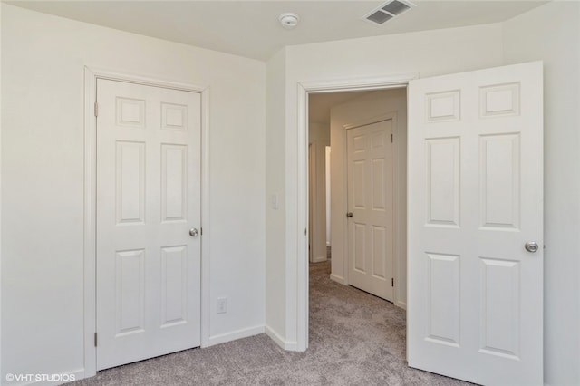 unfurnished bedroom with a closet and light carpet