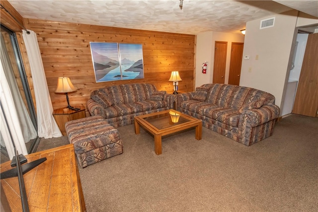 living room with carpet flooring, wood walls, and a textured ceiling