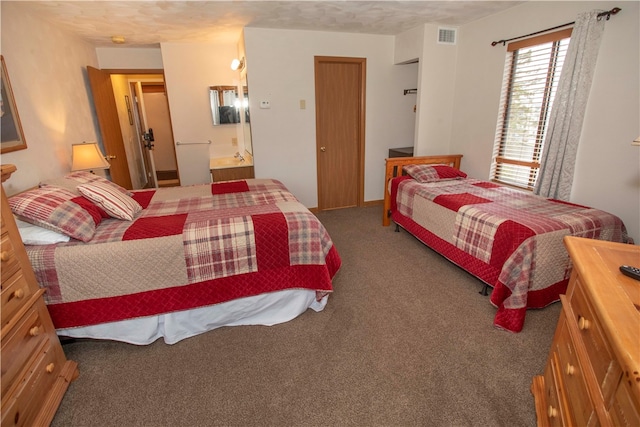 bedroom with dark colored carpet, a textured ceiling, and connected bathroom