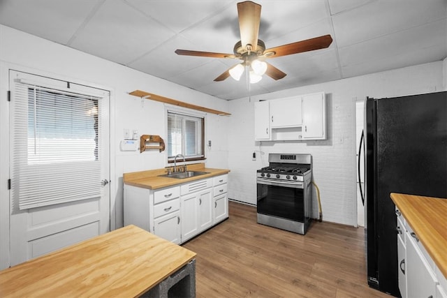 kitchen with ceiling fan, light hardwood / wood-style floors, sink, stainless steel range with gas cooktop, and white cabinetry