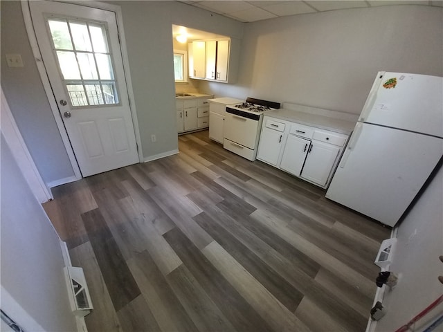 kitchen featuring dark hardwood / wood-style floors, sink, a drop ceiling, white cabinetry, and white appliances