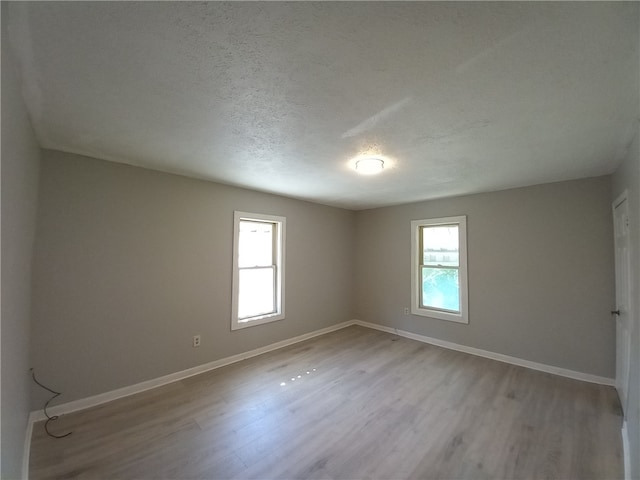 unfurnished room featuring a textured ceiling, light wood-type flooring, and a wealth of natural light