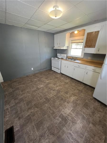 kitchen featuring sink, a drop ceiling, white range with electric stovetop, and white cabinets