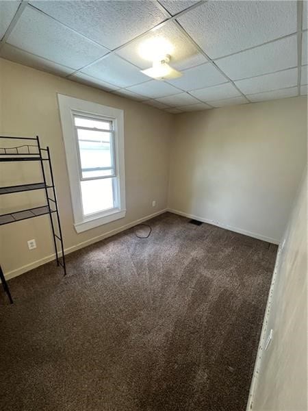 unfurnished room with dark carpet and a paneled ceiling