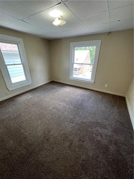 carpeted empty room featuring a paneled ceiling