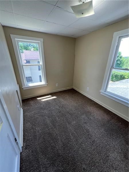 carpeted empty room featuring a paneled ceiling and plenty of natural light