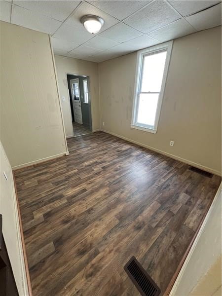 empty room featuring dark wood-type flooring and a paneled ceiling