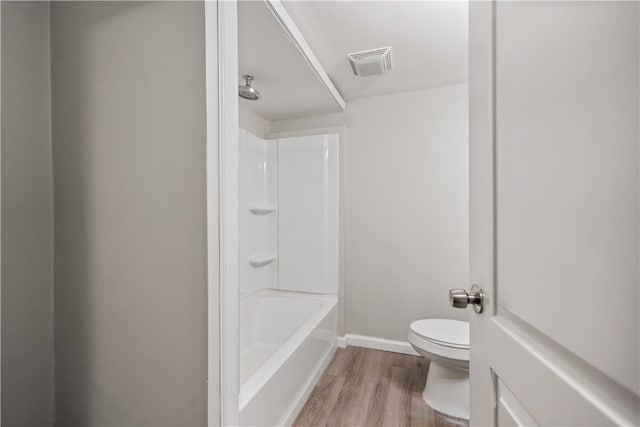 bathroom with  shower combination, hardwood / wood-style floors, and toilet