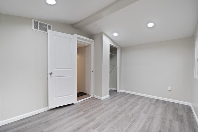 unfurnished bedroom featuring lofted ceiling with beams, light wood-type flooring, and a closet