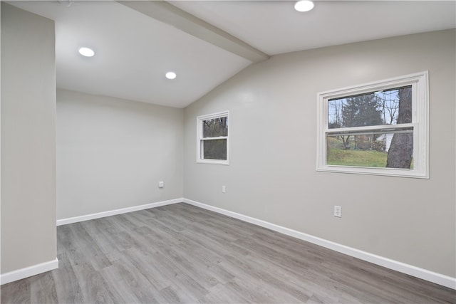 unfurnished room featuring vaulted ceiling with beams and light hardwood / wood-style flooring