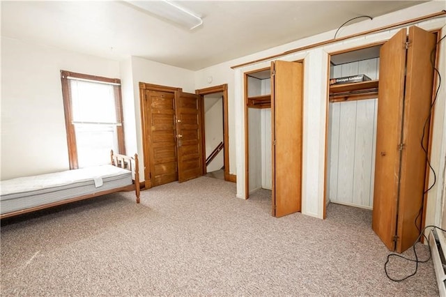 unfurnished bedroom with a baseboard radiator and light carpet