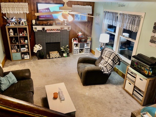 living room featuring wood walls, a brick fireplace, light colored carpet, and ceiling fan