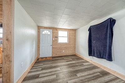 entrance foyer with dark hardwood / wood-style flooring and wooden walls