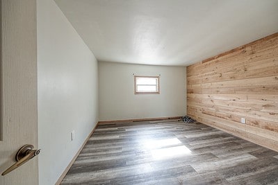 empty room with wood walls and hardwood / wood-style flooring