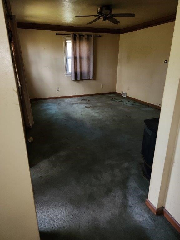 carpeted empty room with a wood stove and ceiling fan