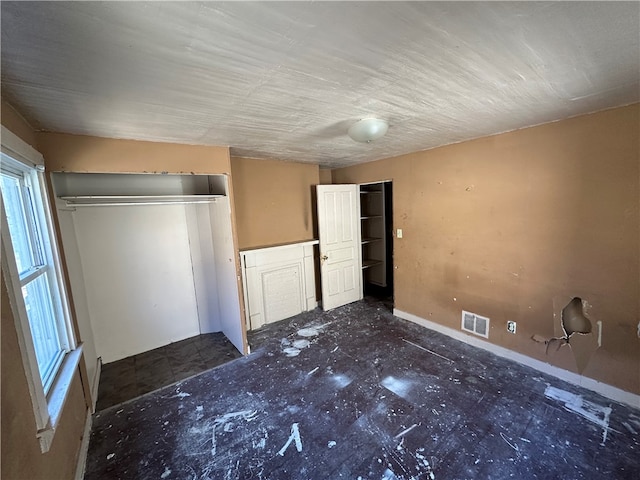 unfurnished bedroom featuring a closet, dark tile floors, and multiple windows