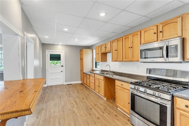 kitchen featuring a drop ceiling, appliances with stainless steel finishes, light wood-type flooring, and sink