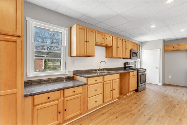 kitchen featuring light brown cabinetry, a drop ceiling, stainless steel appliances, sink, and light hardwood / wood-style flooring