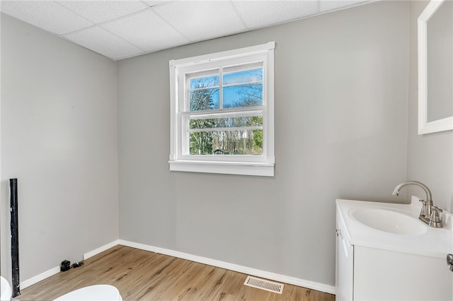 bathroom featuring hardwood / wood-style flooring, a drop ceiling, and vanity