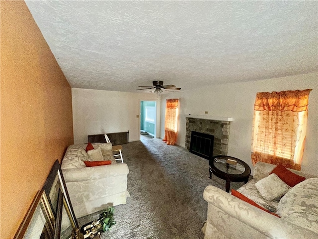 living room featuring a fireplace, a textured ceiling, carpet floors, and ceiling fan