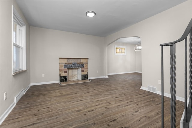 unfurnished living room featuring dark hardwood / wood-style flooring, a fireplace, and a healthy amount of sunlight