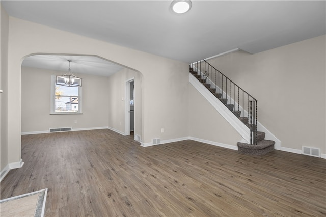 unfurnished living room featuring dark hardwood / wood-style flooring and an inviting chandelier